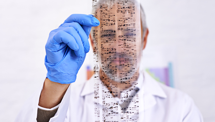 Un científico sosteniendo una transparencia con los resultados de una prueba de ADN