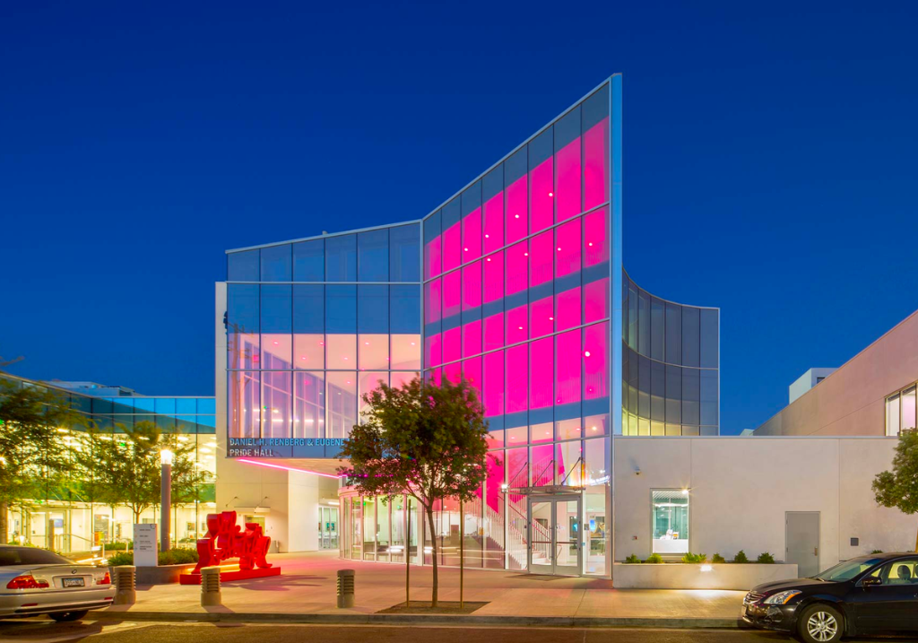 a modern assymmetrical building with pink lighting against the night sky