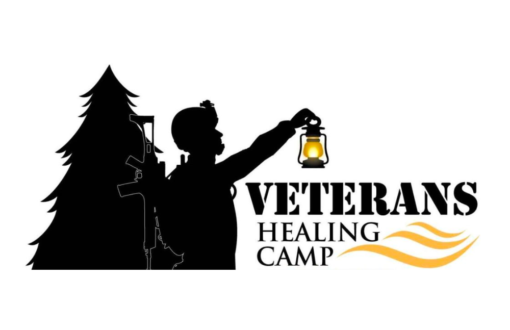 Black illustration of a silhouette of a pine tree and person with a lamp with the words 'Veteran's Healing Camp' inscribed underneath. 