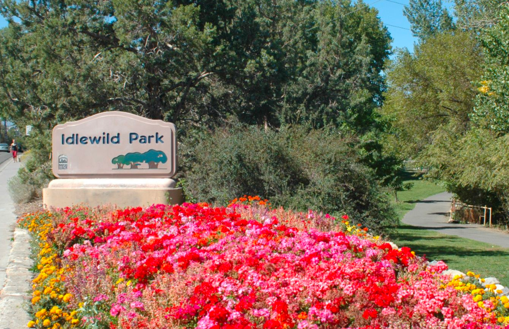 Flowerbed brim with pink and red blooms and a sign for Idlewild Park