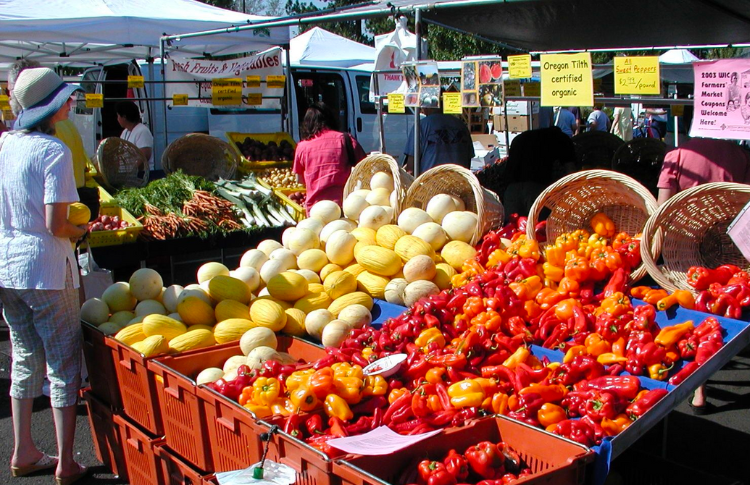 An array of yellow, orange, and red fruits and vegetables in an open market setting.