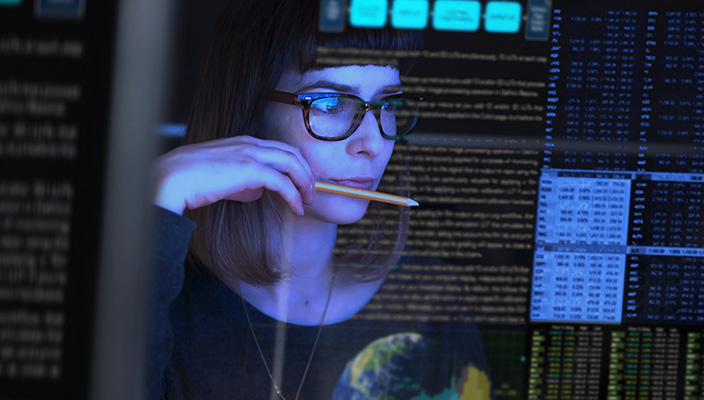Una persona mirando la pantalla de una computadora. En la pantalla se reflejan documentos y tablas de datos.