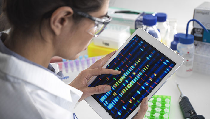 Una especialista de un laboratorio revisa resultados de ADN en una tableta.