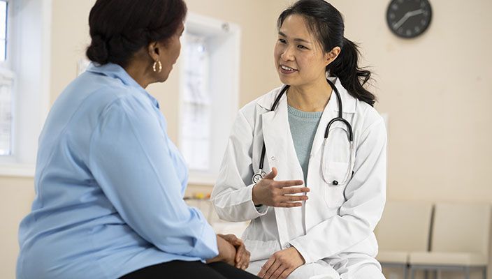 A physician is talking to a female patient at her medical office.
