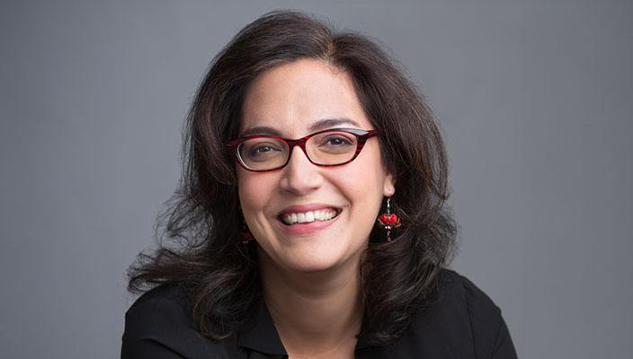 Portrait of Dr. Laura Germine, who smiles at the camera. She is wearing glasses.