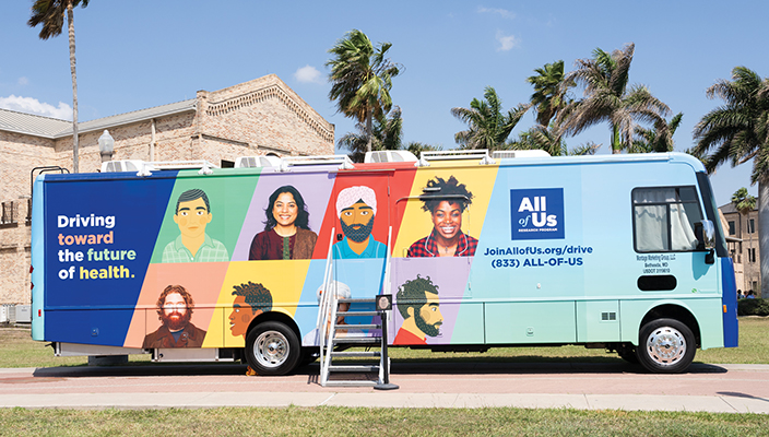 Un bus de promoción del Programa Científico All of US está estacionado en una calle, en un día soleado. El costado del bus contiene dibujos y fotos de los rostros de personas de distintas razas y etnicidades.