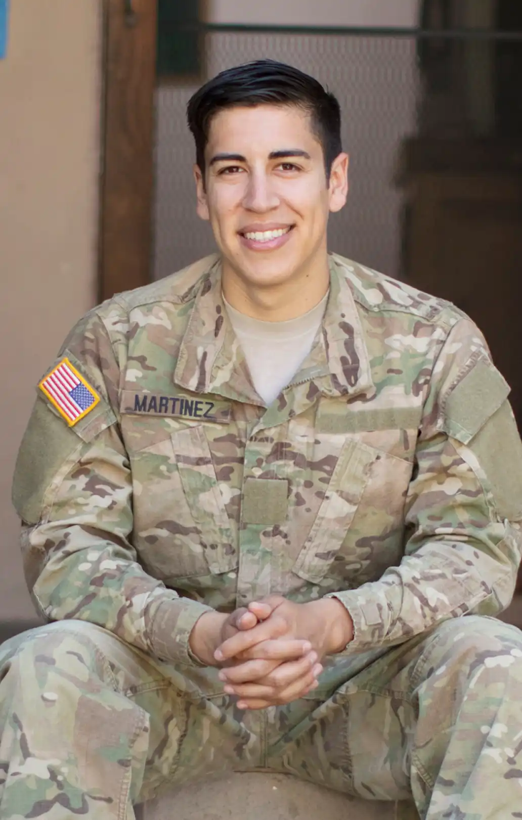 Hispanic man in Army uniform sitting on the front steps of a home